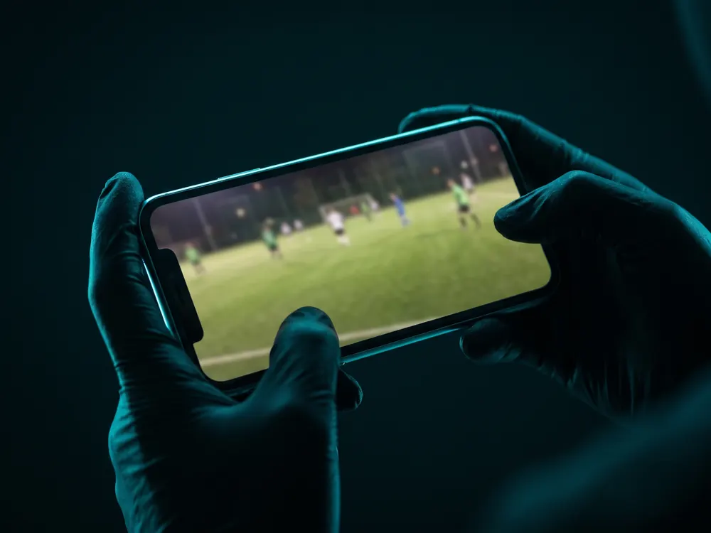 Dos manos sosteniendo el celular acostado, filmando un partido.
